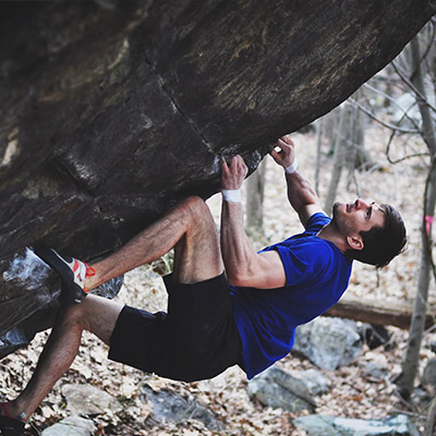 Instructor Charlie Schreiber free climbing rock in the woods