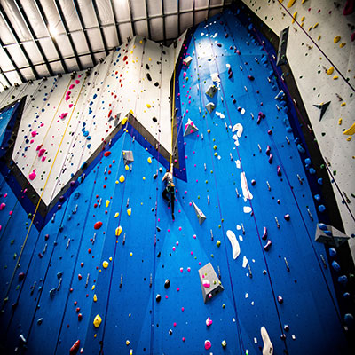 blue rock climbing wall with person climbing