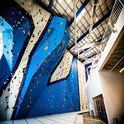 blue and gray rock climbing wall with colorful grips