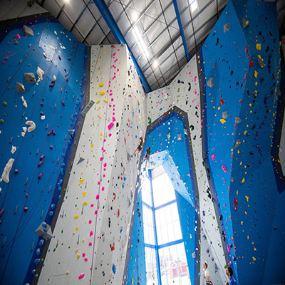 blue and gray rock climbing wall with 2 students rock climbing