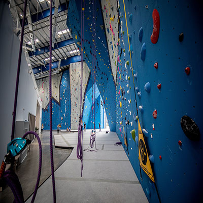 blue rock climbing wall with ropes hanging down