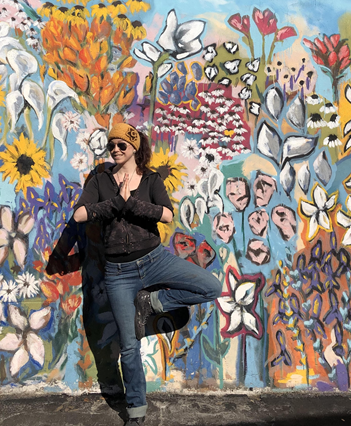 yoga instructor in pose with painted flower wall in background